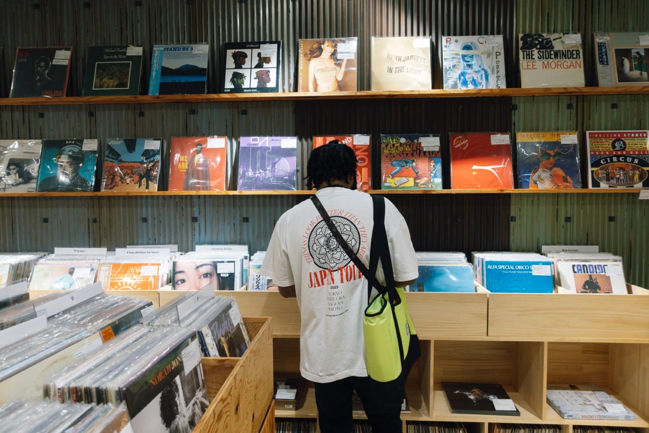 A photo of Paul Chin digging for vinyl in a Tokyo record store. His back is turned toward the camera